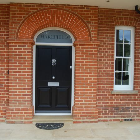 Black entrance door surrounded by brick