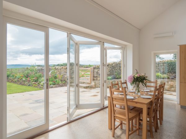 large set of white bifold timber doors with views over the garden and countryside beyond