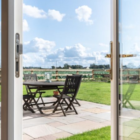 french doors half open onto the garden patio and fields beyond