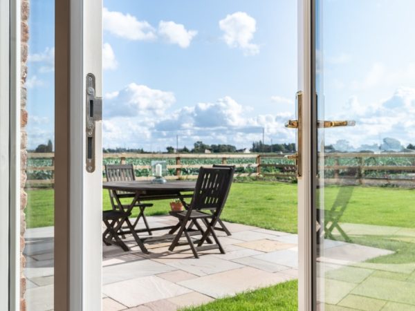 french doors half open onto the garden patio and fields beyond