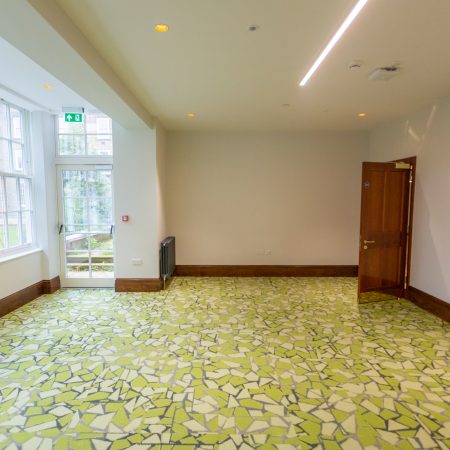 Large communal area showing span of sliding sash windows and a timber fire escape door