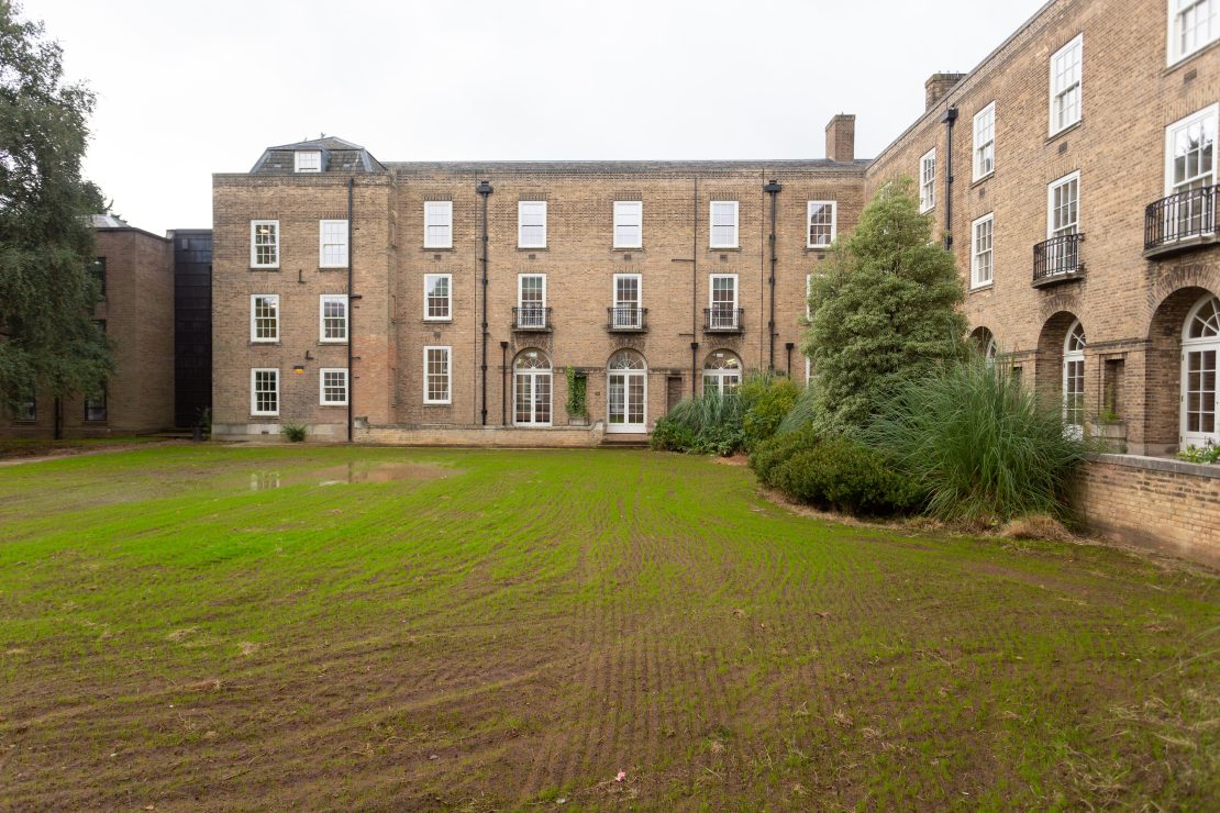 External shot of building showing numerous sash windows and sets of arched french doors.