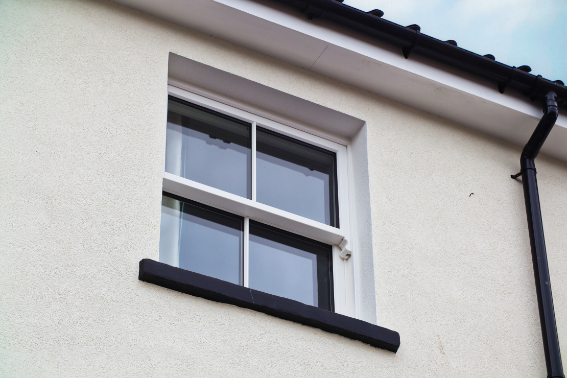 close up of external timber sliding sash window with lambs tongue glazing bars. Painted white. Accoya timber