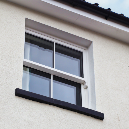 close up of external timber sliding sash window with lambs tongue glazing bars. Painted white. Accoya timber