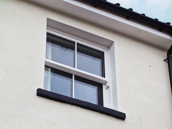 close up of external timber sliding sash window with lambs tongue glazing bars. Painted white. Accoya timber