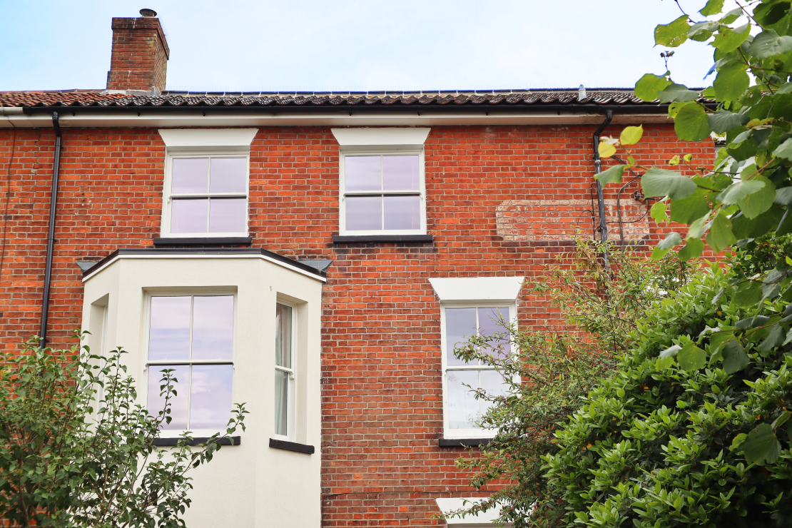 front external shot of top two floors with sliding sash bay window and two smaller sash windows above